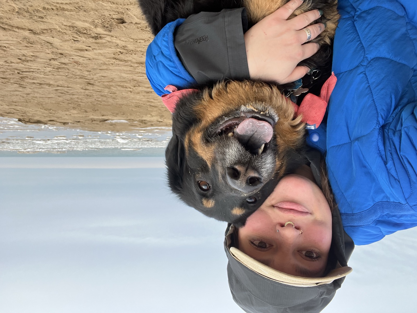 Taylor hugging Gobi on the beach in winter coats, both smiling
